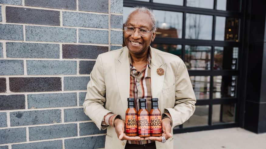 Mr. Levi holding all three flavors of Soul Sauce outside Capital City Market